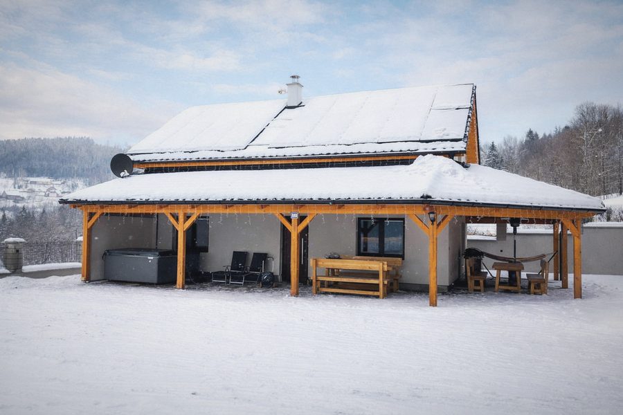 Chalupa se solárními panely pod sněhem, krytá terasa s posezením