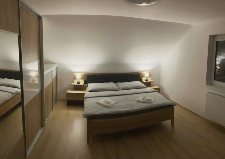 Ložnice s manželskou postelí, nočními lampami a skříní se zrcadlem